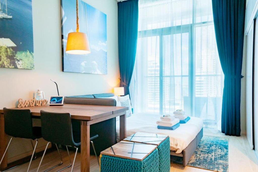 a room with a desk and a bed with blue curtains at Marina Studio with Sea Views - Close to Beach in Dubai