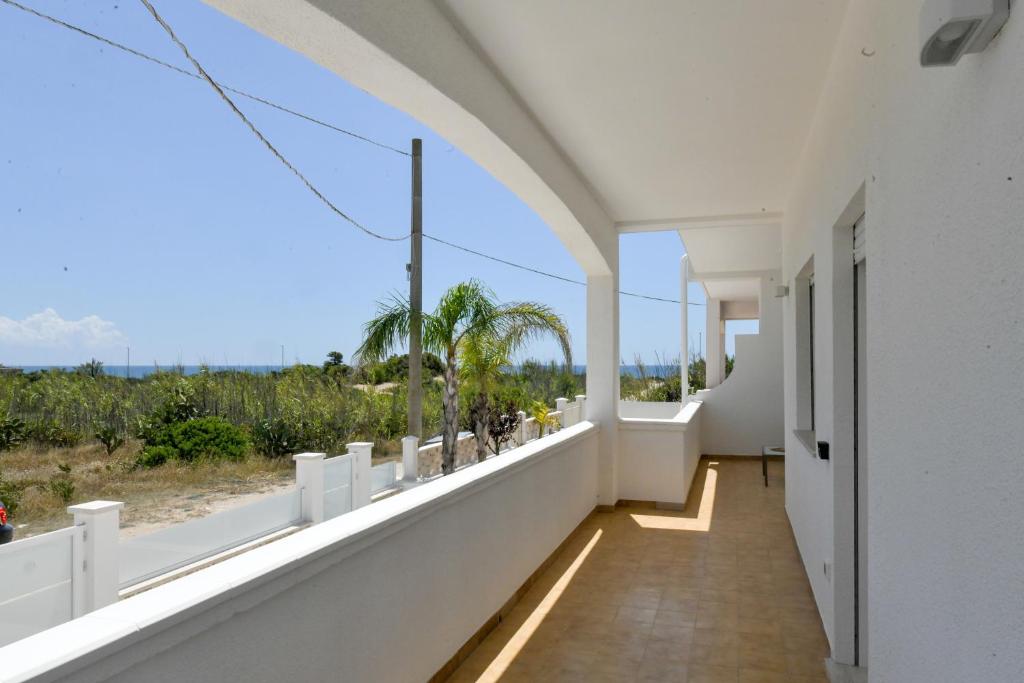 een kamer met een balkon met uitzicht op de oceaan bij SINE TEMPORE Beach Holiday Home in Maruggio