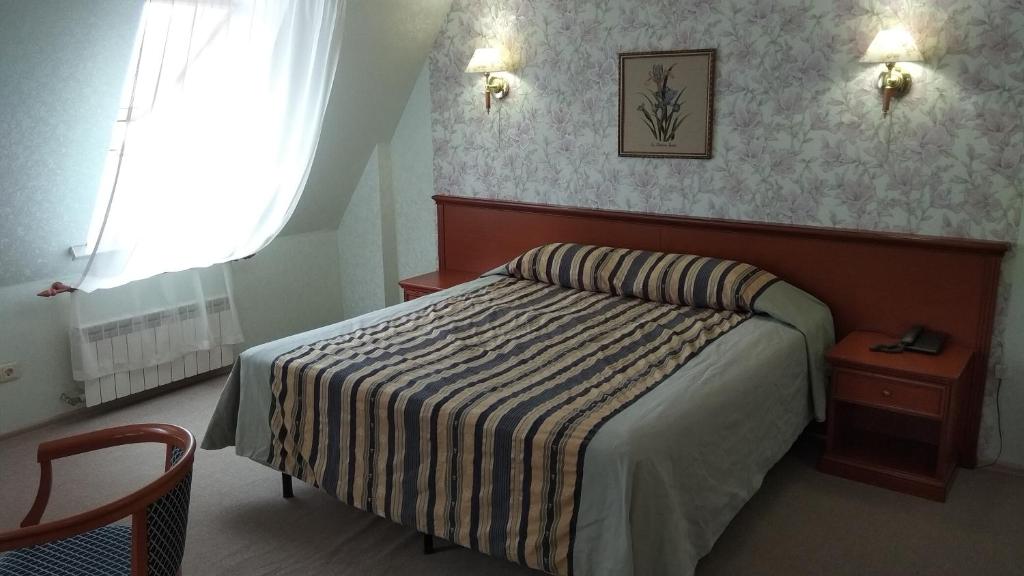 a small bedroom with a bed and a window at Tea Rose Hotel in Yekaterinburg