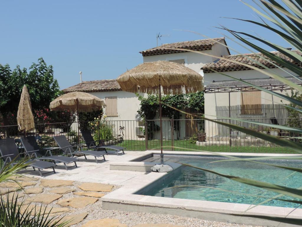 a house with a swimming pool with chairs and umbrellas at 22 aout au 12 sept loc 2 ch, clim, piscine 11 x 5 vue Luberon in Cavaillon