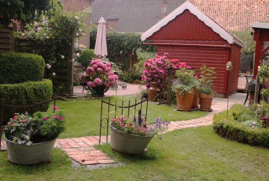 a garden with pots of flowers and a red shed at Alte Pastorei in Hinte