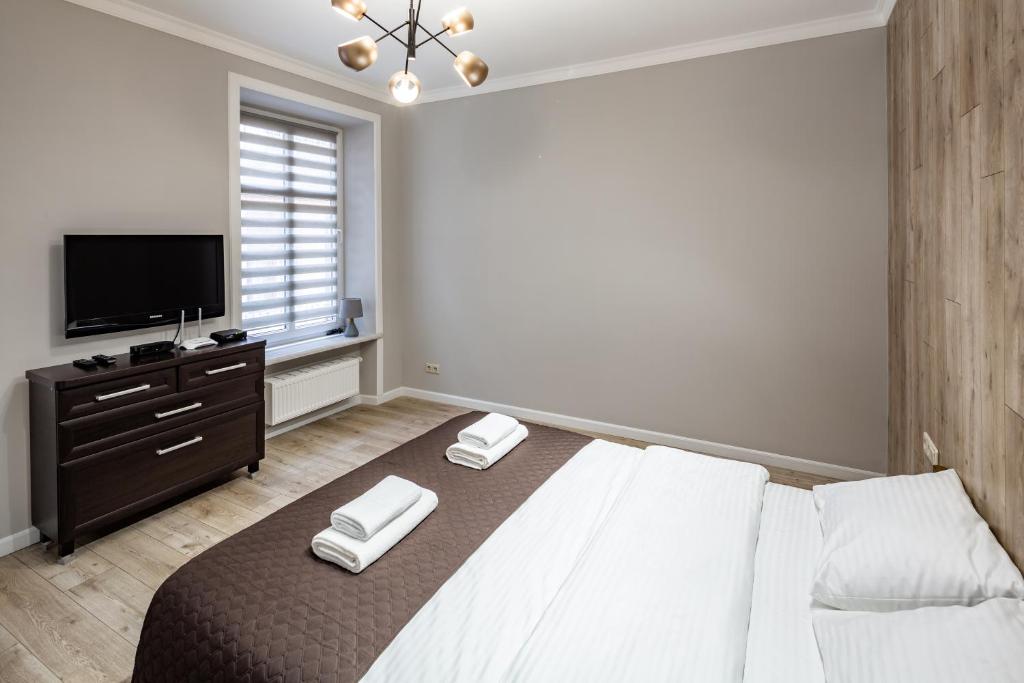 ein Schlafzimmer mit einem großen Bett und einem TV in der Unterkunft Rynok Square Apartments in Lwiw