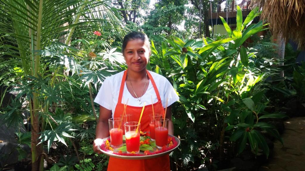 a woman holding a tray with drinks on it at Zopango Orchids Island in Isletas de Granada
