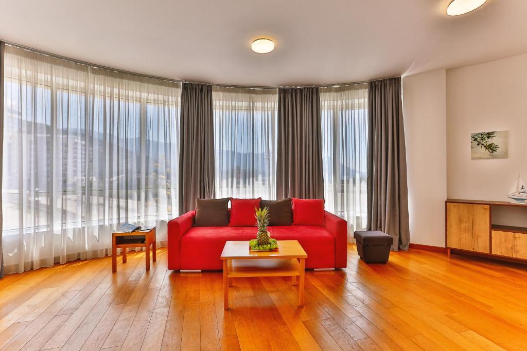 ein Wohnzimmer mit einem roten Sofa und großen Fenstern in der Unterkunft Seaside Rest Apartments in Budva