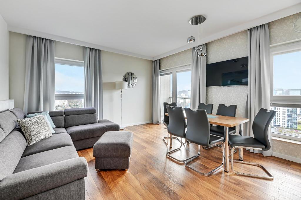 a living room with a couch and a table and chairs at Wave Apartments - Albatros in Gdańsk