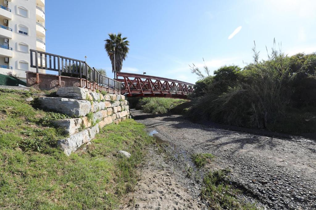 a bridge over a river with a building and palm tree at Banana Beach primera línea de playa in Marbella