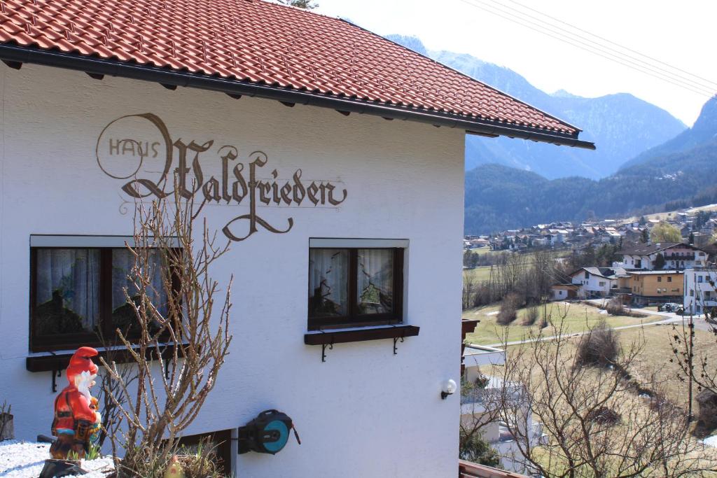 un bâtiment blanc avec un panneau sur son côté dans l'établissement Haus Waldfrieden, à Sautens