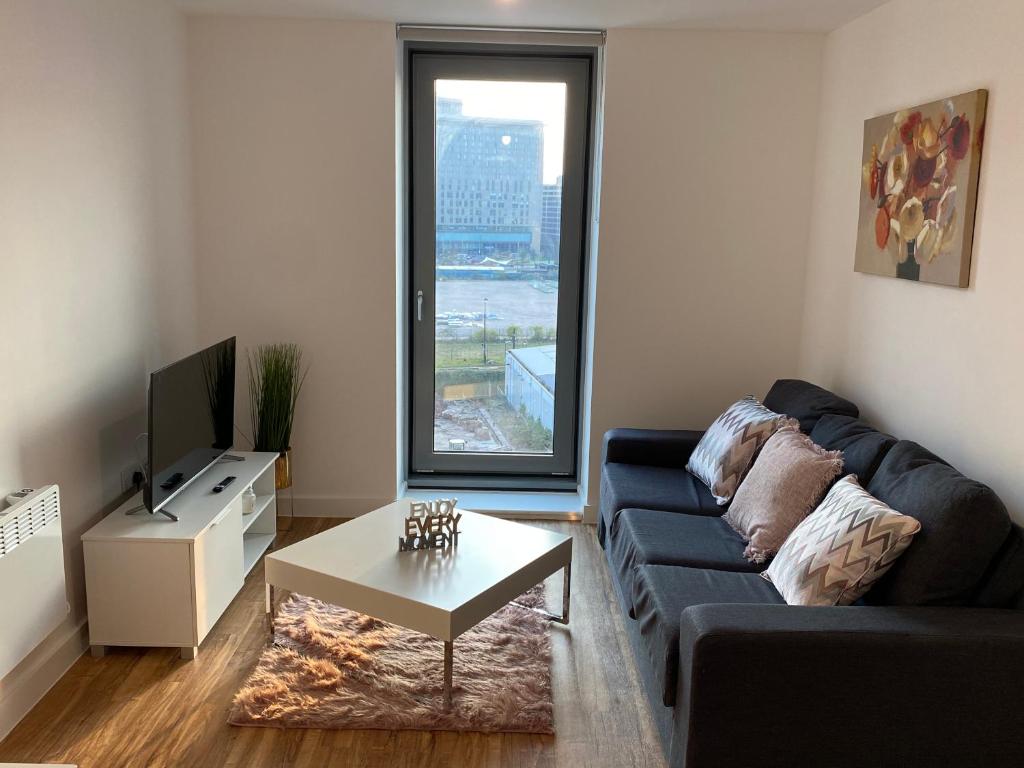 a living room with a couch and a tv and a table at 1 bedroom lovely apartment in Salford quays free street parking subject to availability in Manchester