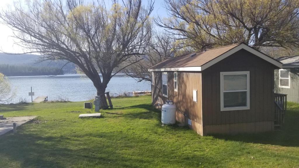 a small shack in the grass next to a lake at Willow Bay RV Resort & Marina in Nine Mile Falls