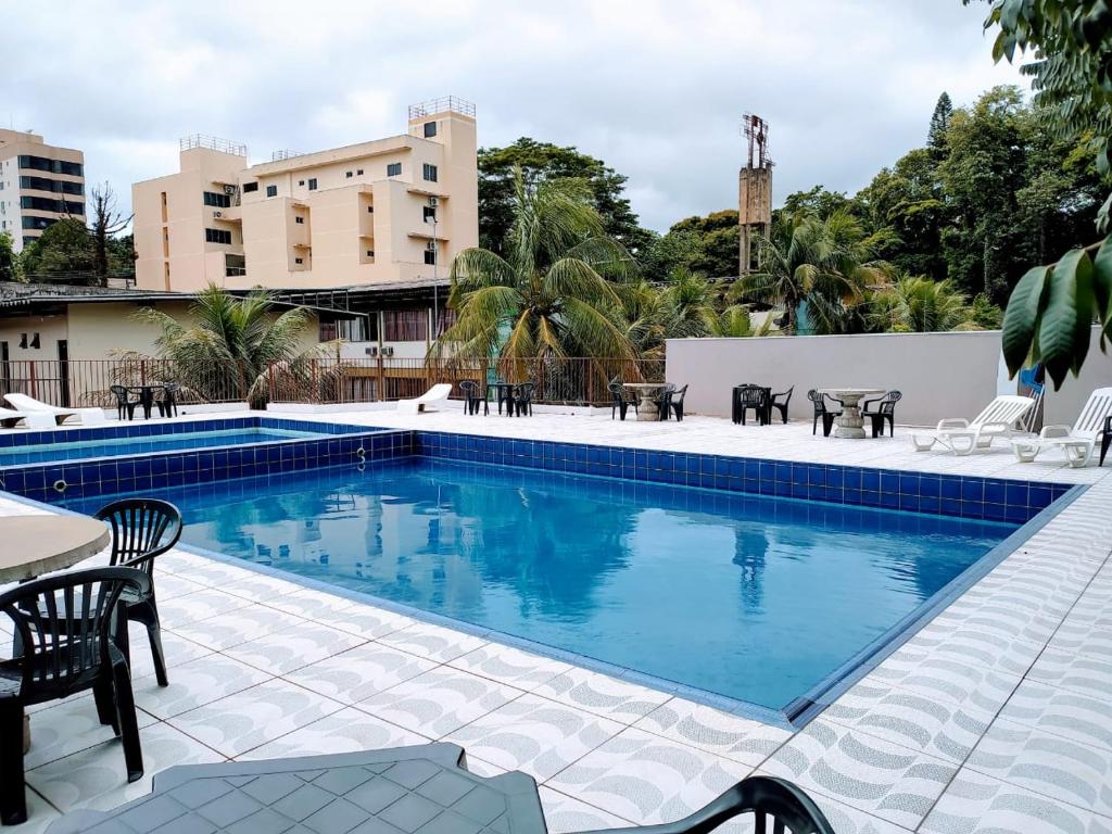 una piscina con sillas y mesas junto a un edificio en Hotel Natureza Foz, en Foz do Iguaçu