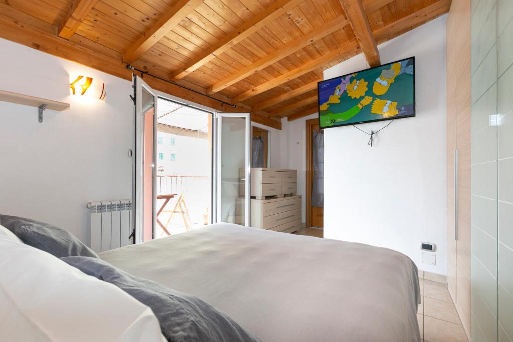 1 dormitorio con 1 cama y TV en la pared en Giardi, en Riomaggiore