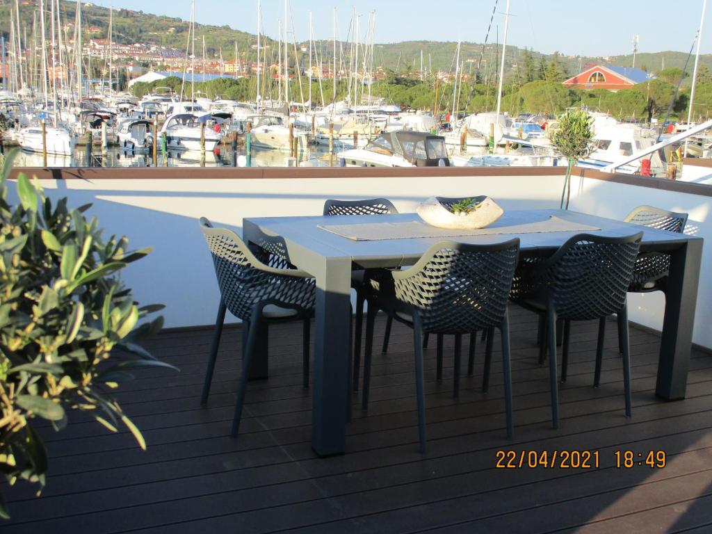 a table and chairs on a deck with a marina at Sunset floating house in Portorož