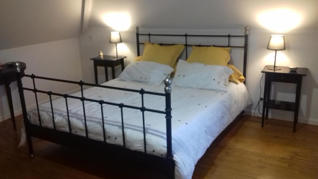 1 dormitorio con cama negra y almohadas amarillas en Colline, en Serres-Castet