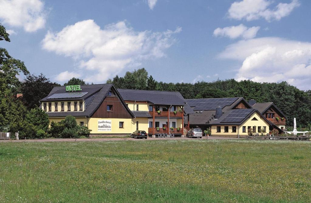 um grupo de edifícios com um campo à sua frente em Familienhotel Brandtsheide em Jeserig