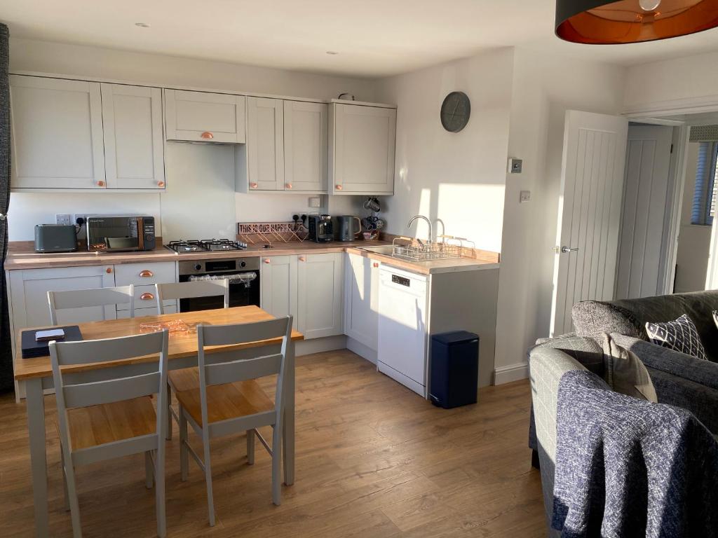 a kitchen with white cabinets and a table and chairs at Bay - Brambles Chine, Colwell Bay - 5 star WiFi - Short walk to The Hut and beach - 1 night stays available - Ferry offers in Freshwater