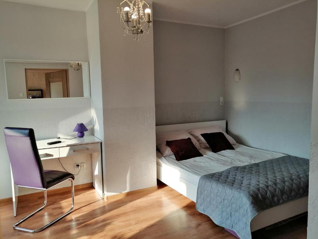 een slaapkamer met een bed, een bureau en een stoel bij Apartament Wiosenna in Malbork