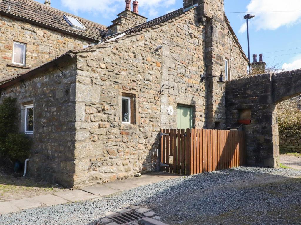 an old stone building with a gate in front of it at Beehive Cottage in High Bentham