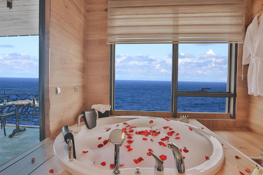 a bathroom with a tub with a view of the ocean at Peerless Villas Hotel in Trabzon