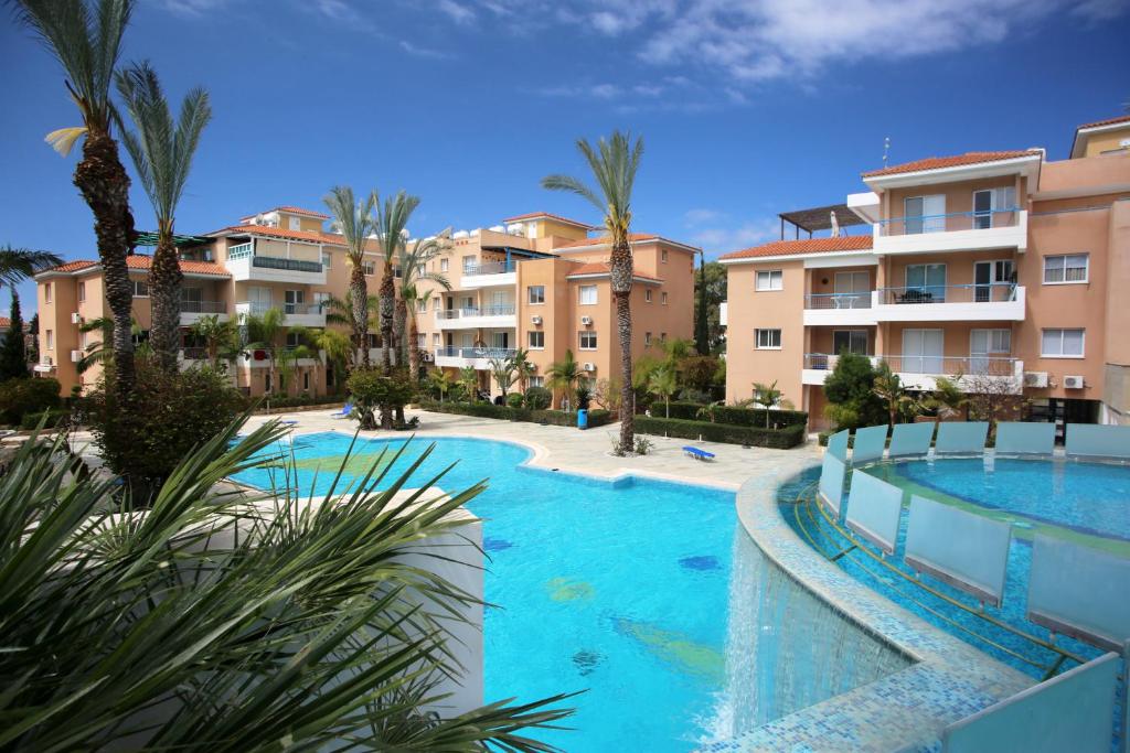 een zwembad met palmbomen en gebouwen bij Apartment Iris Village Kato Paphos in Paphos