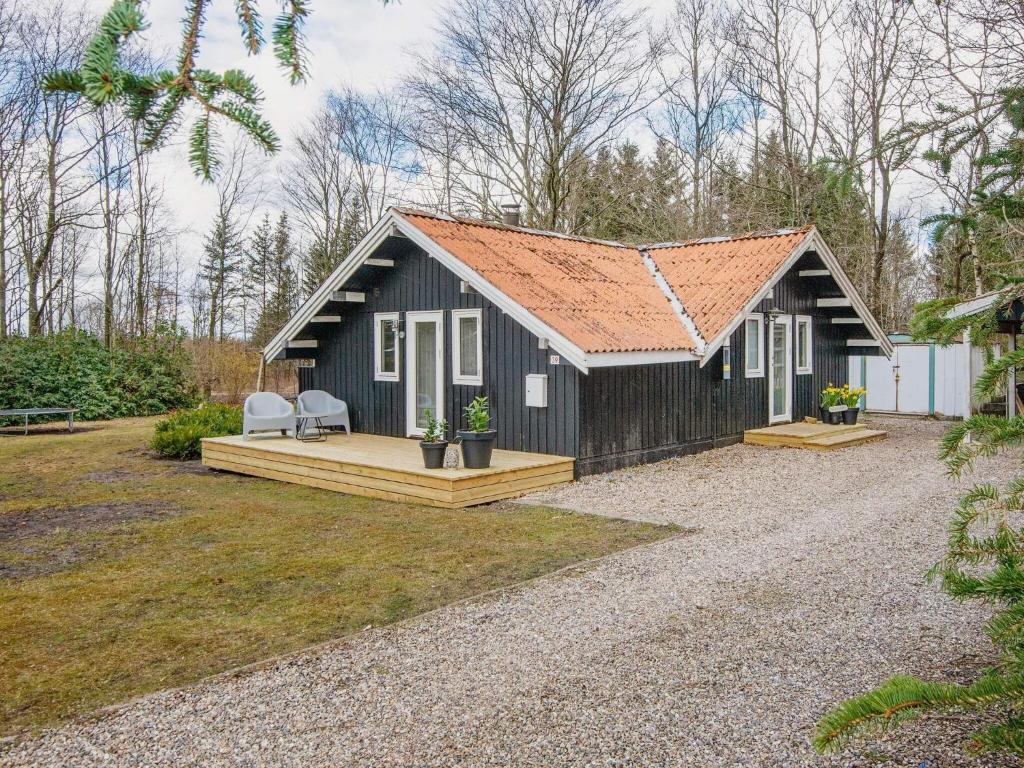 Vestergårdにある6 person holiday home in Toftlundのデッキと椅子2脚付きの黒いコテージです。