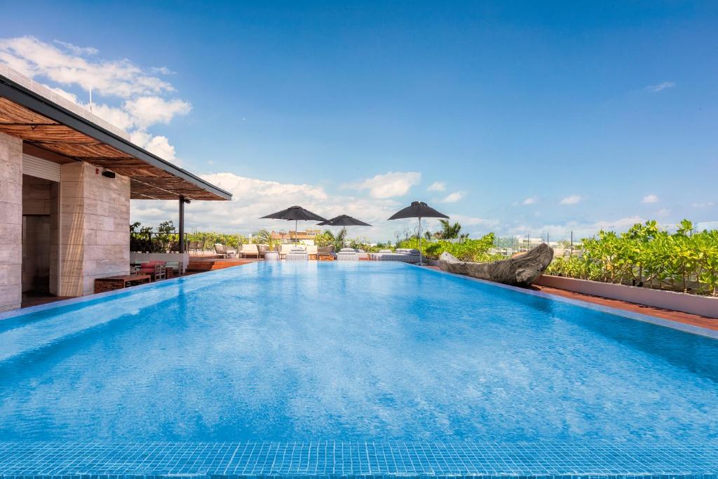 a swimming pool at a resort with umbrellas at The Yucatan Resort Playa del Carmen, All-Inclusive Adults Only, Tapestry by Hilton in Playa del Carmen