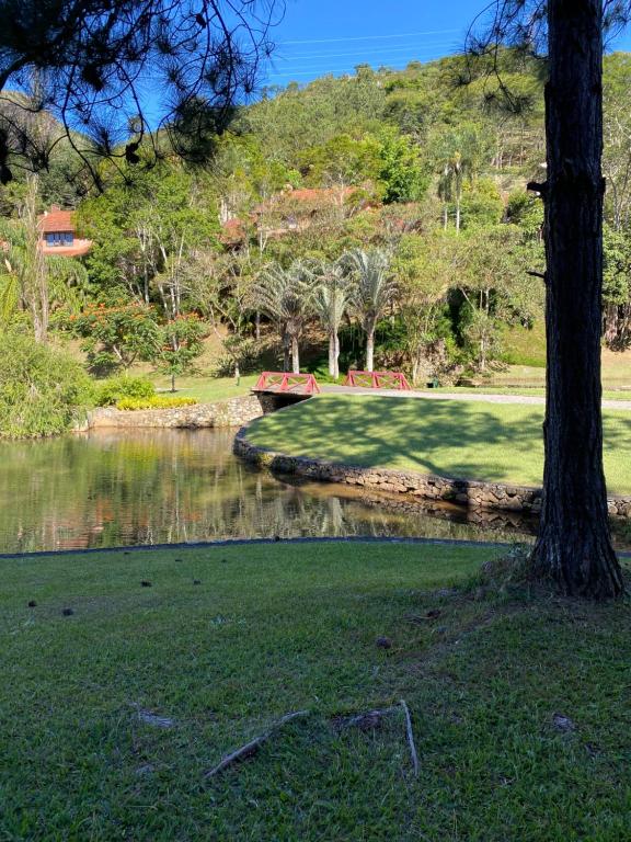 um parque com um lago e uma árvore e uma ponte em Chalé Quinta do Lago em Petrópolis