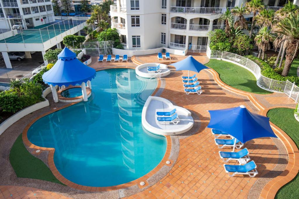 an overhead view of a swimming pool with blue chairs and umbrellas at BreakFree Moroccan in Gold Coast