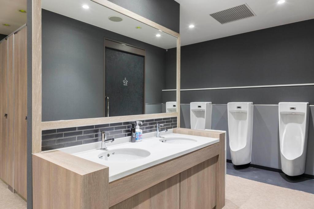 a bathroom with two sinks and a mirror and urinals at TUBE Sq in Tokoname