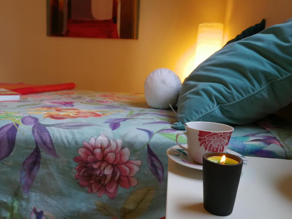 a candle and a cup on a table next to a bed at WELCOME TO DISCOVER THE MAGIC AMAZING TENERIFE !! PRIVATE BATH NICE BREAKAST WF :) in Candelaria