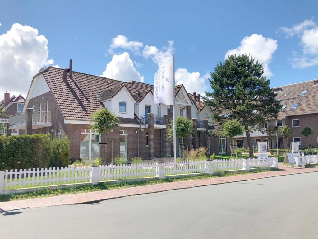 ein Haus mit einem weißen Zaun davor in der Unterkunft Hotel Upstalsboom Langeoog in Langeoog