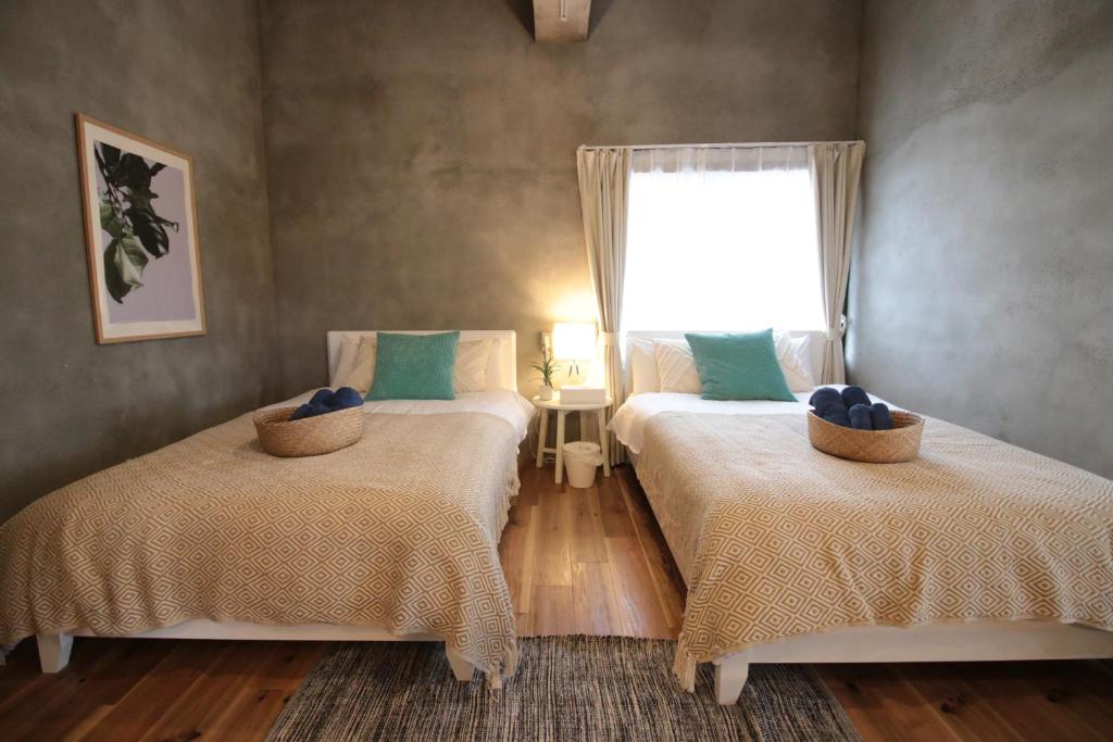 1 dormitorio con 2 camas y ventana en Plus Life Ishigaki, en Ishigaki Island
