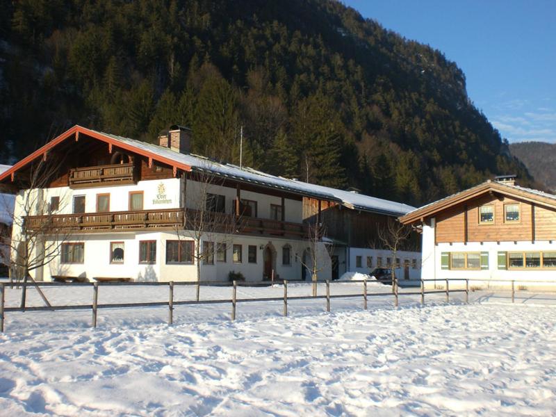 ein Gebäude im Schnee vor einem Berg in der Unterkunft Kilianhof in Berchtesgaden