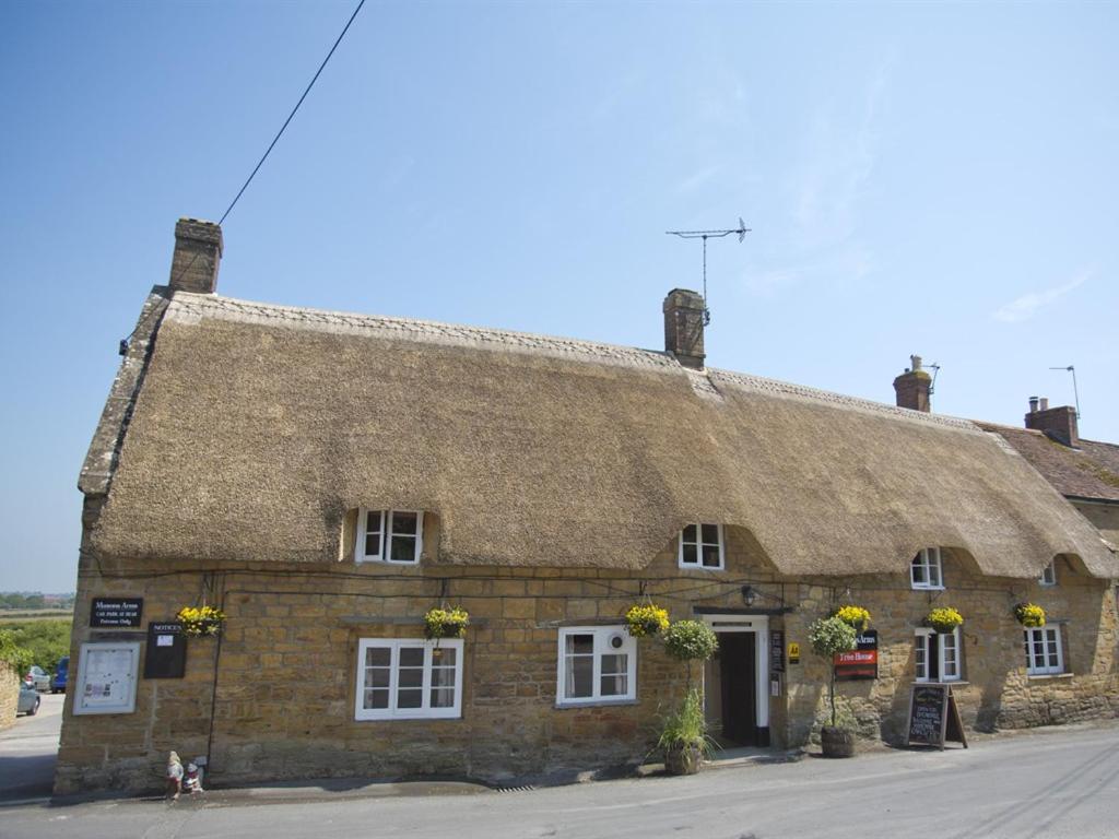 an old stone building with a thatched roof at The Masons Arms in Yeovil