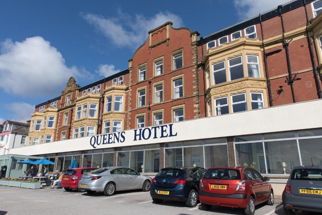 un edificio con coches estacionados frente a un hotel en Queens Hotel, en Blackpool