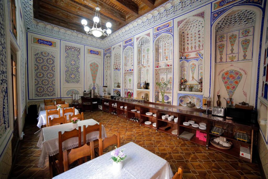 a restaurant with tables and chairs in a room with colorful walls at Kavsar Boutique Hotel in Bukhara