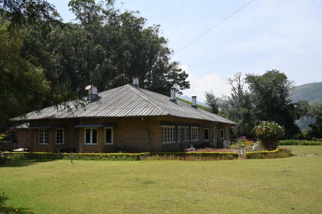 une maison dans un champ à côté d'une cour dans l'établissement Ama Stays and Trails Tea Estate Bungalows , Munnar, à Munnar