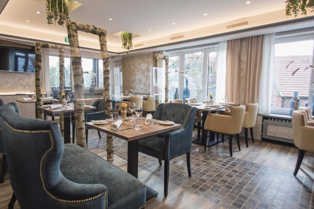 een restaurant met tafels, stoelen en ramen bij Schwiizeralp Hotel & Restaurant in Stemwede