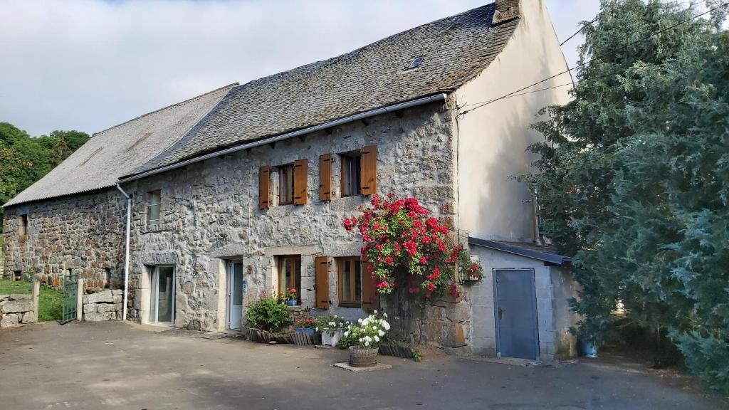 stary kamienny dom z kwiatami przed nim w obiekcie maison individuelle au calme sur l'Aubrac w mieście Recoules-dʼAubrac