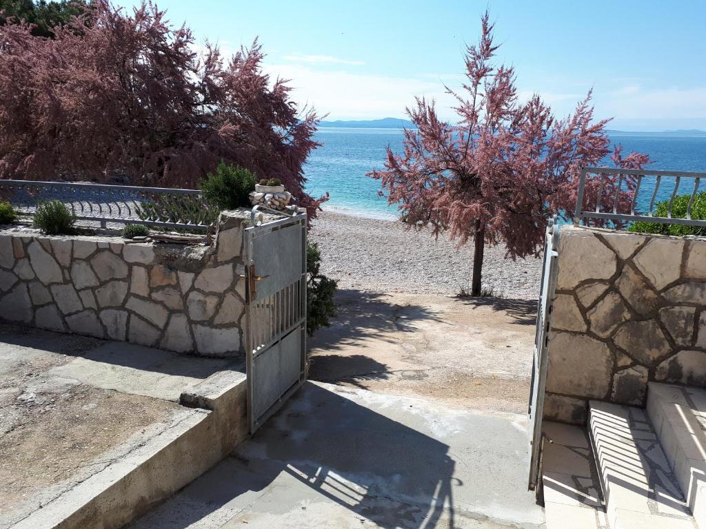um portão para uma praia com o oceano ao fundo em On the Beach Ivan Dolac em Ivan Dolac