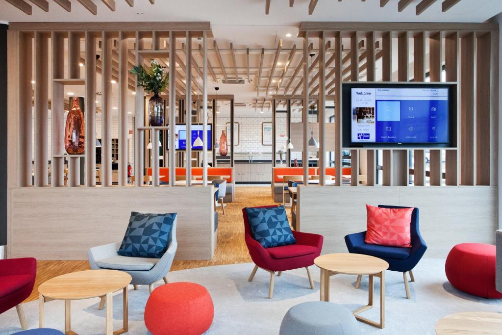 a lobby with chairs and tables and a tv at Holiday Inn Express - Offenburg, an IHG Hotel in Offenburg