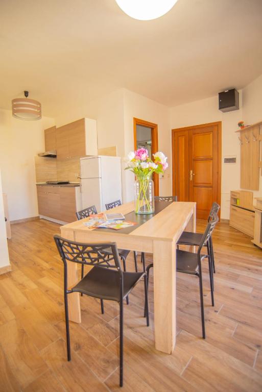 a dining room table with chairs and a vase of flowers at Valery Apartments Alghero in Alghero
