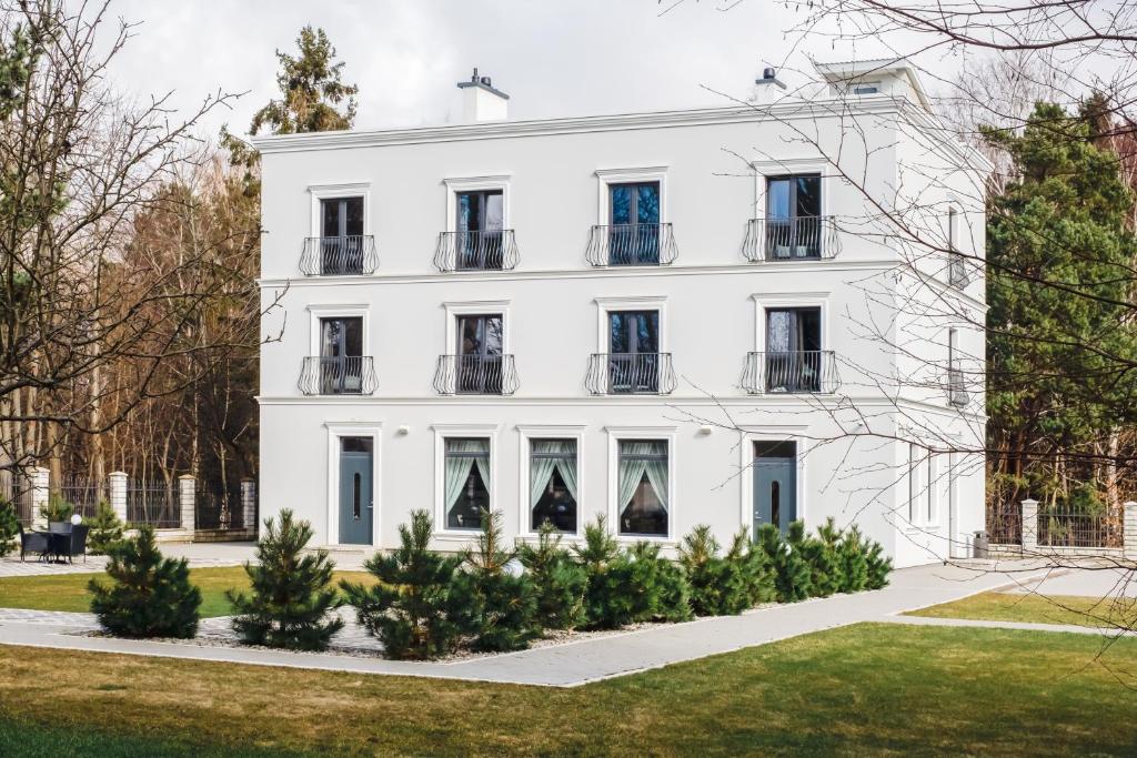 uma casa branca com árvores em frente em FOREST PALANGA RESORT em Palanga