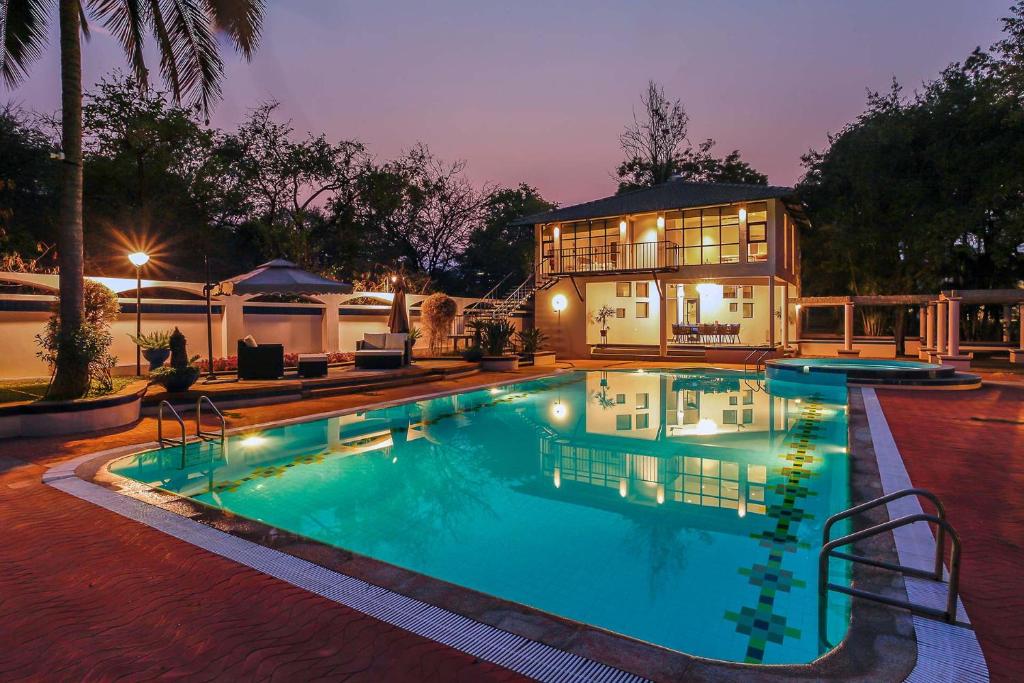a house with a swimming pool in front of a house at StayVista at Ananta - Breakfast Included & Basketball Court in Bangalore