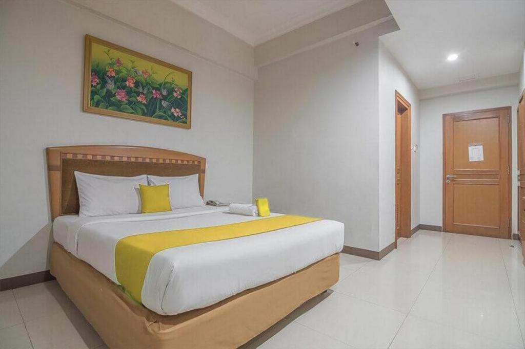 ein Schlafzimmer mit einem großen Bett und einem Gemälde an der Wand in der Unterkunft Hotel Yehezkiel Surapati Mitra RedDoorz in Bandung