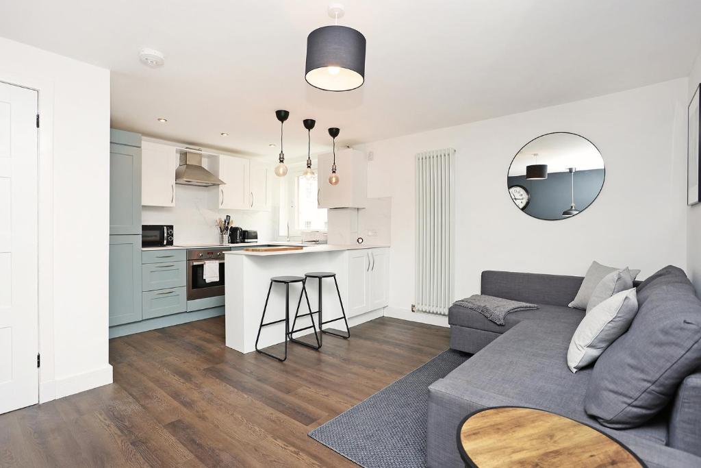 uma sala de estar com um sofá cinzento e uma cozinha em JOIVY Contemporary Royal Mile Apartment with Balcony em Edimburgo