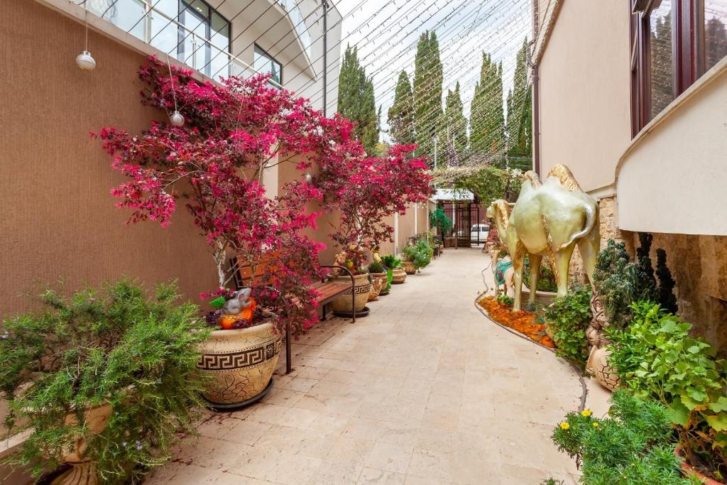 a walkway in a greenhouse with flowers and a cow statue at Дубай in Adler