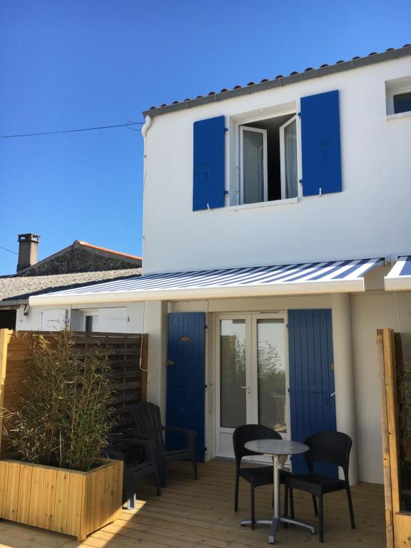 a patio with chairs and a table in front of a house at Les Bains Boyardville - Hôtel et Restaurant in Boyard-Ville