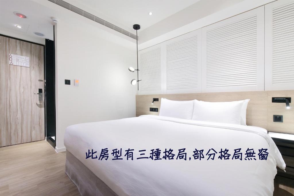 um quarto com uma grande cama branca com escrita chinesa em KEEBE Hotel em Keelung