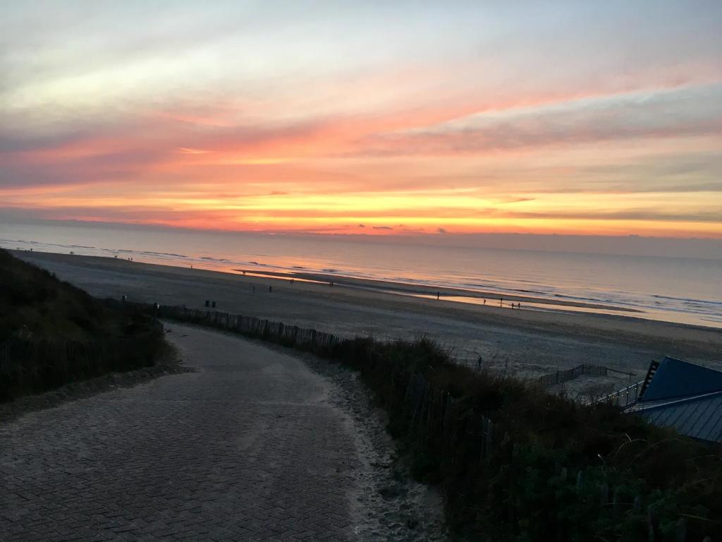 - un coucher de soleil sur la plage avec un chemin menant à la plage dans l'établissement The Palmtree, à Zandvoort