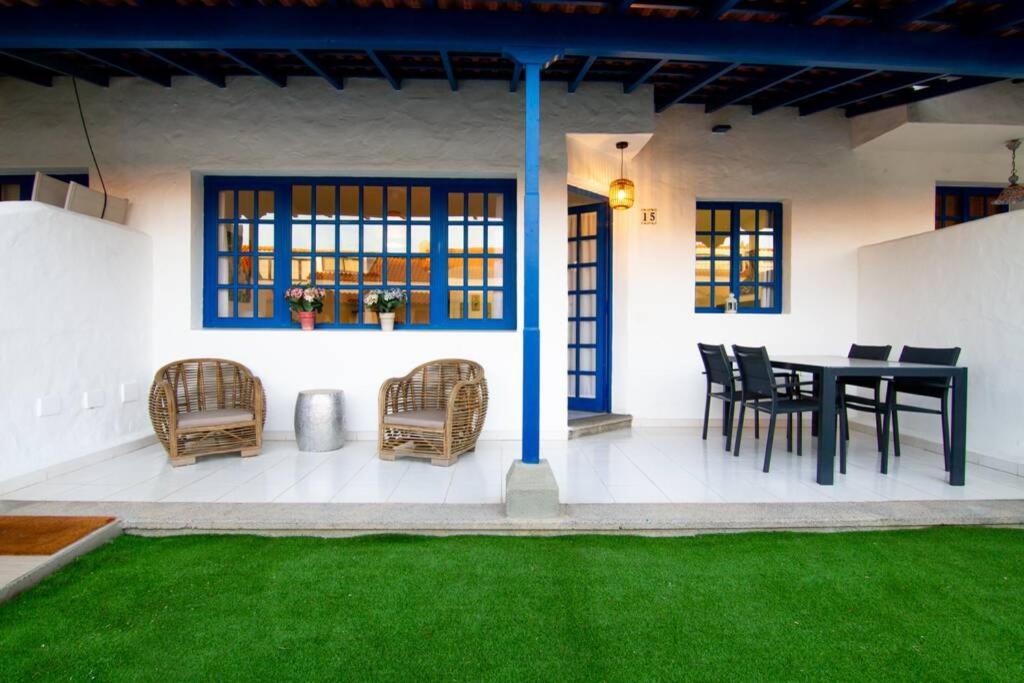 a patio with a black table and chairs and green grass at Bungalow en Pasito V15 in Pasito Blanco